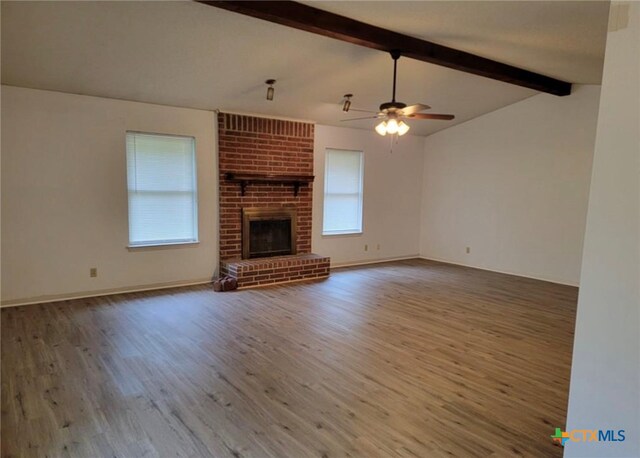 unfurnished living room with a fireplace, wood-type flooring, ceiling fan, and lofted ceiling with beams