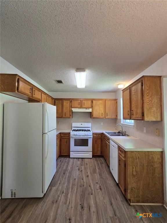4709 Poppy Wood Cir, Killeen, TX 76542 - kitchen featuring white appliances, a sink, under cabinet range hood, a textured ceiling, and dark wood finished floors
