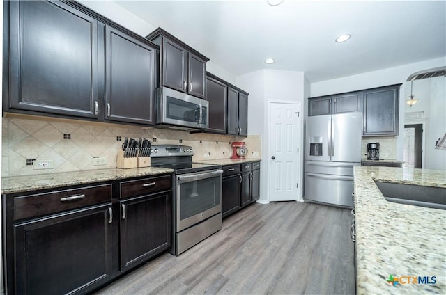 232 Pevero, Cibolo, TX 78108 - kitchen with appliances with stainless steel finishes, light wood-style flooring, a sink, decorative backsplash, and light stone counters