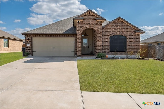 view of front of property with a garage, brick siding, driveway, and a front lawn