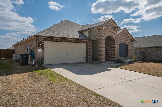 view of front of house with an attached garage, brick siding, fence, concrete driveway, and roof with shingles