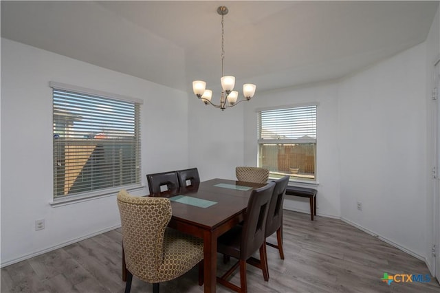 dining space with wood finished floors and an inviting chandelier