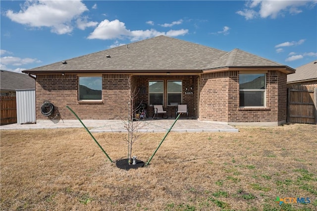 back of house featuring a patio area, roof with shingles, fence, and brick siding