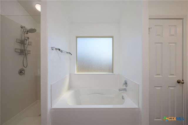 bathroom with a stall shower and a garden tub