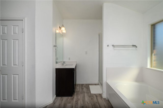 bathroom with a garden tub, vanity, a shower stall, and wood finished floors