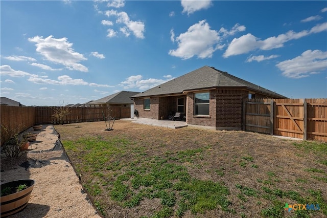 back of house featuring brick siding, a patio area, and a fenced backyard