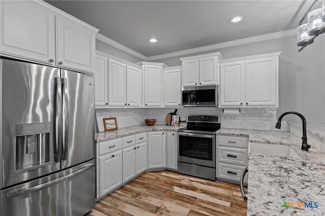 kitchen with sink, tasteful backsplash, ornamental molding, appliances with stainless steel finishes, and white cabinets