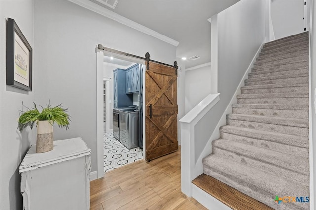 stairway with separate washer and dryer, crown molding, wood-type flooring, and a barn door