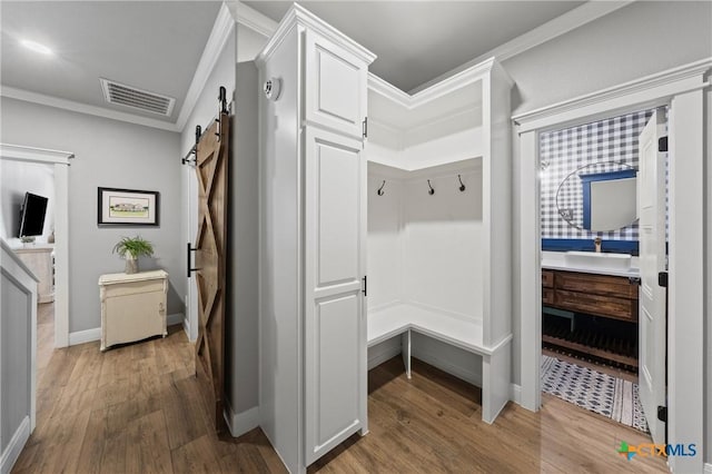 mudroom with hardwood / wood-style flooring, crown molding, a barn door, and sink