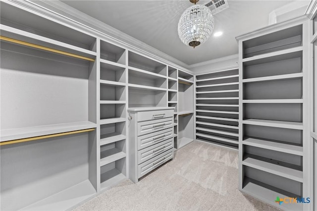 walk in closet with light colored carpet and a chandelier