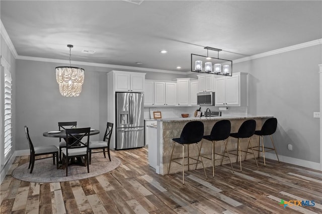 kitchen featuring hanging light fixtures, white cabinetry, appliances with stainless steel finishes, and a kitchen bar