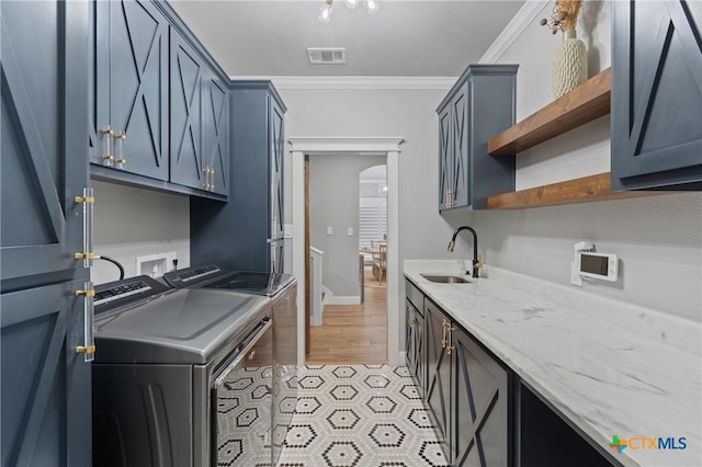 kitchen featuring light stone counters, ornamental molding, sink, and washer and dryer