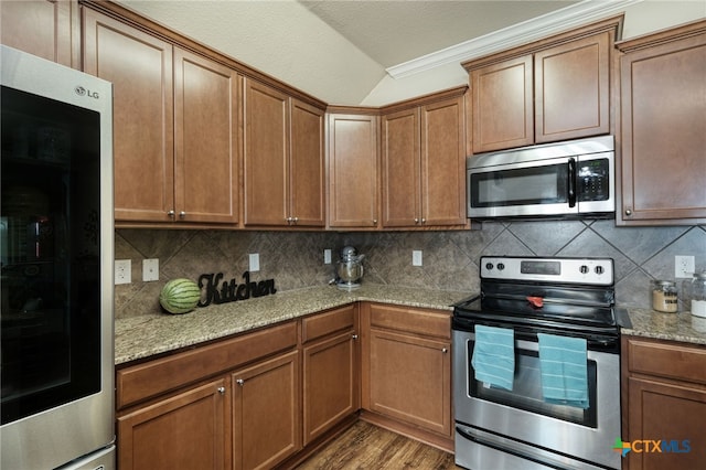 kitchen featuring backsplash, hardwood / wood-style flooring, ornamental molding, light stone counters, and stainless steel appliances