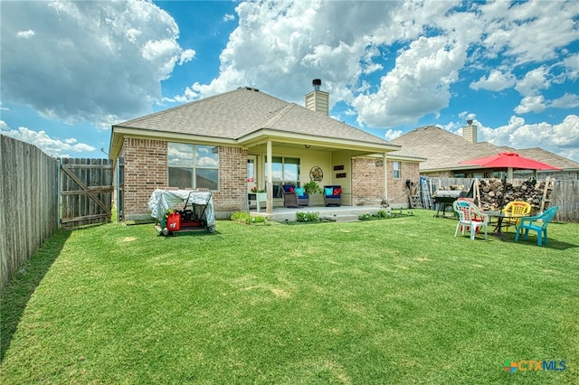 rear view of house featuring an outdoor living space, a patio area, and a lawn