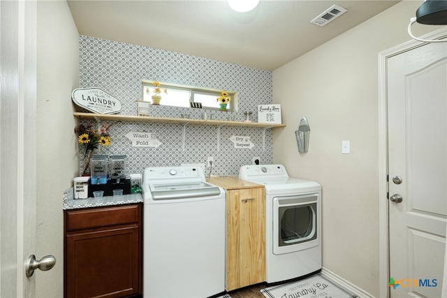 clothes washing area with washer and dryer and cabinets