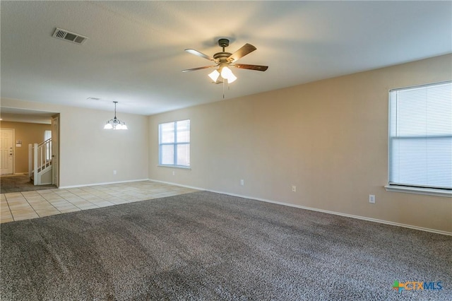 carpeted spare room with ceiling fan with notable chandelier