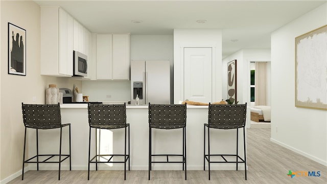 506 Bonzo Ct, Jarrell, TX 76537 - kitchen with a peninsula, appliances with stainless steel finishes, a breakfast bar, and light wood-style flooring