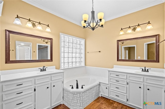 bathroom with tiled tub, hardwood / wood-style flooring, crown molding, vanity, and a chandelier