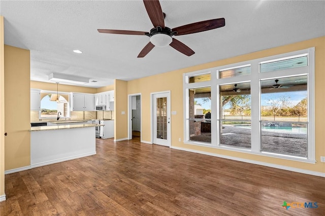 unfurnished living room featuring sink, dark hardwood / wood-style floors, and ceiling fan