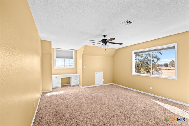 additional living space featuring ceiling fan, lofted ceiling, light carpet, and a textured ceiling