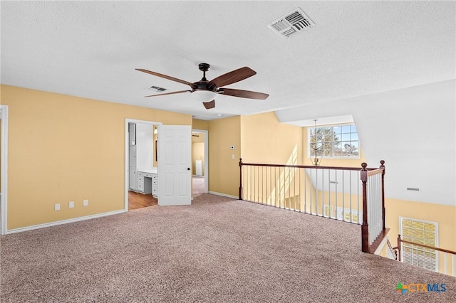 unfurnished room featuring lofted ceiling, light colored carpet, a textured ceiling, and ceiling fan