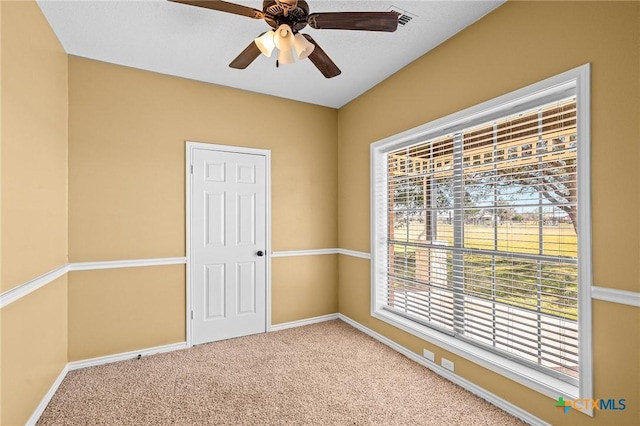 carpeted spare room featuring a wealth of natural light and ceiling fan