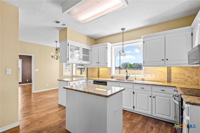 kitchen featuring pendant lighting, stainless steel appliances, a kitchen island, and white cabinets