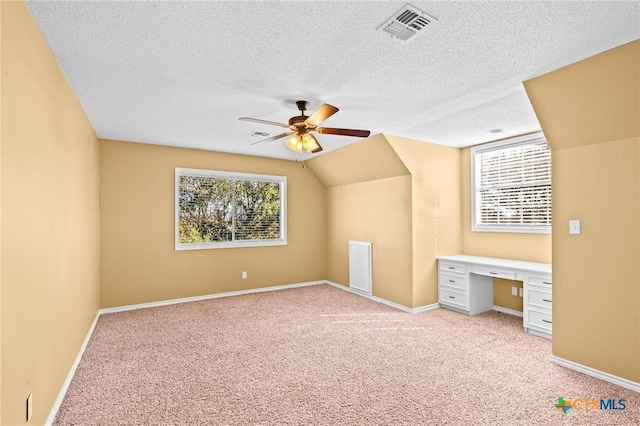 additional living space featuring ceiling fan, vaulted ceiling, light colored carpet, and a healthy amount of sunlight