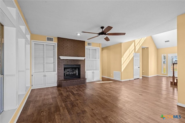 unfurnished living room with a brick fireplace, built in shelves, hardwood / wood-style floors, and ceiling fan