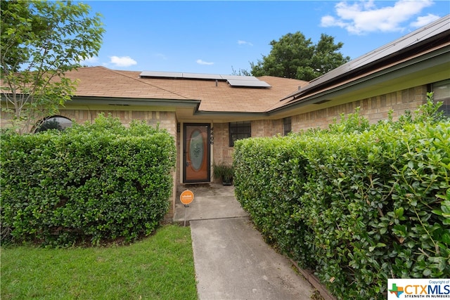 doorway to property with solar panels and a lawn