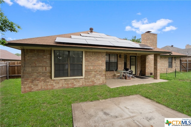 rear view of property featuring solar panels, a yard, and a patio area