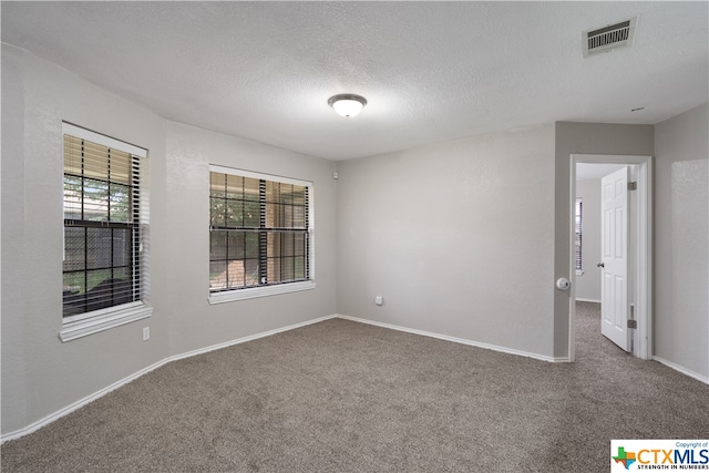 carpeted empty room featuring a textured ceiling