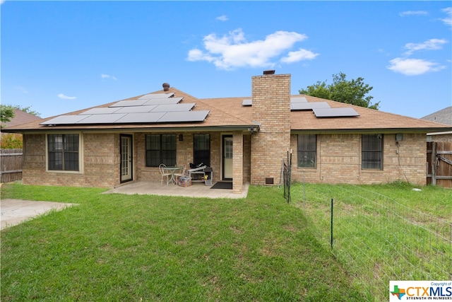 rear view of house with solar panels, a lawn, and a patio