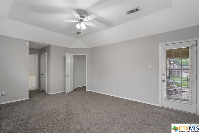 interior space with access to exterior, dark carpet, ceiling fan, and a raised ceiling