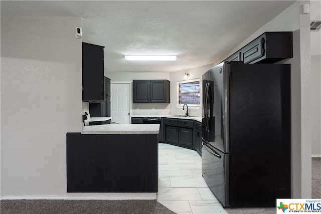 kitchen with a textured ceiling, light colored carpet, sink, and stainless steel fridge