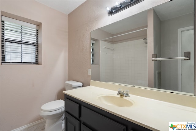 bathroom featuring toilet, vanity, and a tile shower