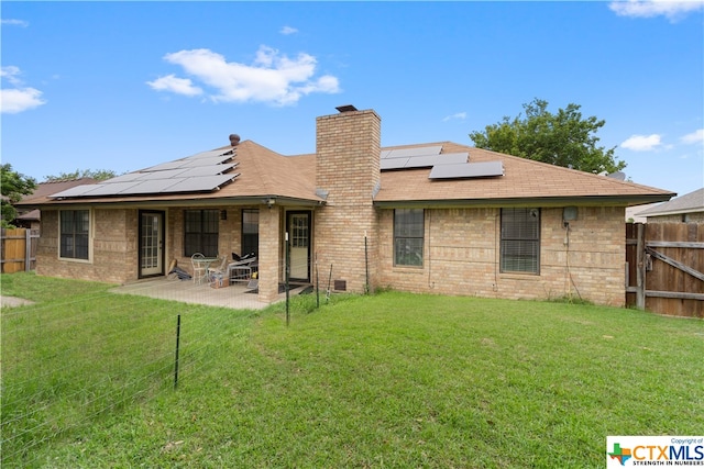 rear view of house featuring solar panels, a patio, and a yard