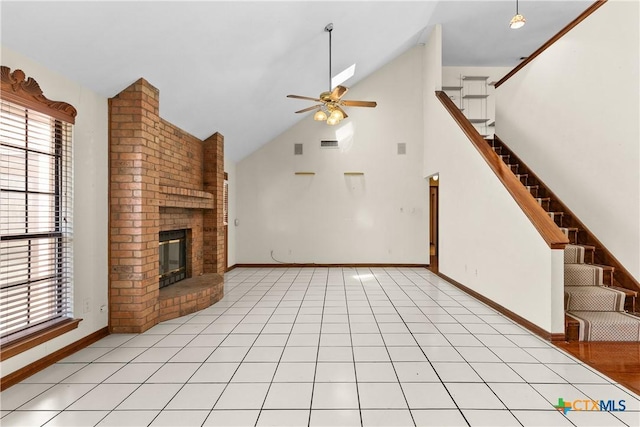 unfurnished living room with a ceiling fan, a fireplace, stairway, and light tile patterned floors