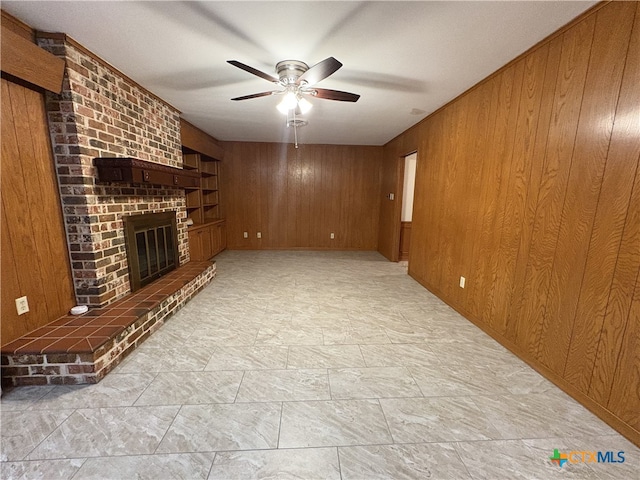 2602 Miori Ln, Victoria, TX 77901 - unfurnished living room with wood walls, ceiling fan, and a fireplace