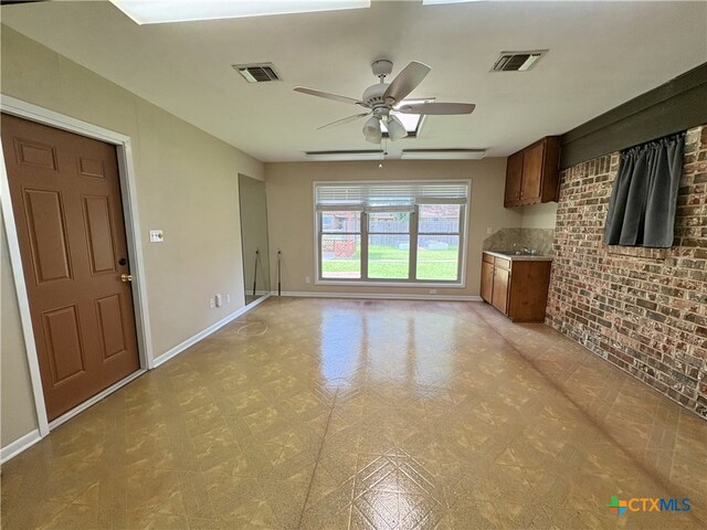 2602 Miori Ln, Victoria, TX 77901 - unfurnished living room with baseboards, a ceiling fan, brick wall, and light flooring