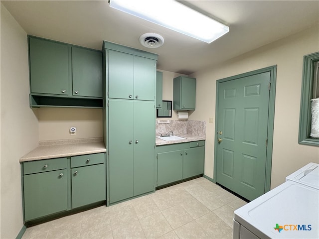2602 Miori Ln, Victoria, TX 77901 - kitchen with green cabinets, washer and dryer, a sink, and light countertops