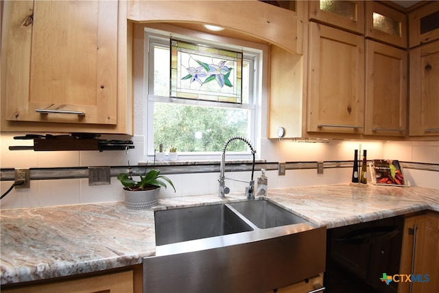 kitchen with light stone countertops, sink, and black dishwasher