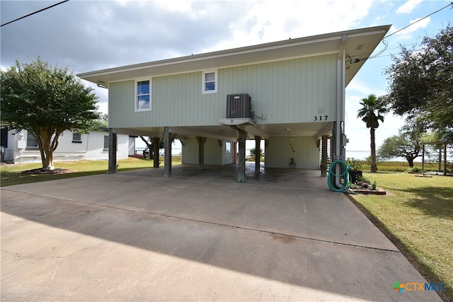 view of front facade with central air condition unit, a carport, and a front yard