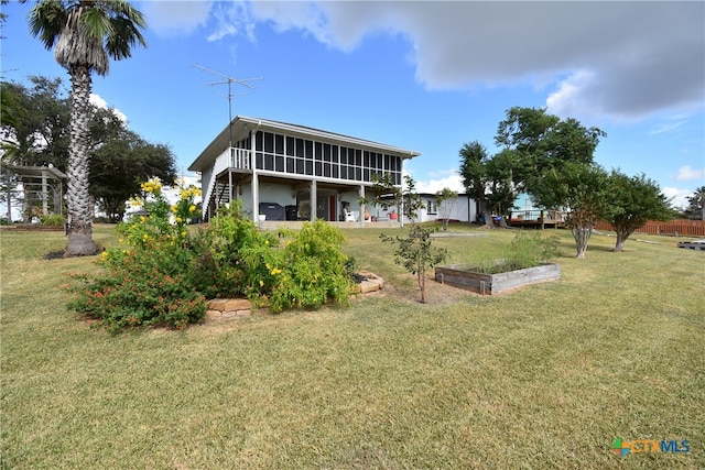 rear view of property with a sunroom and a yard