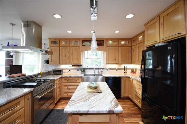 kitchen featuring light hardwood / wood-style floors, black appliances, a kitchen island, and decorative light fixtures