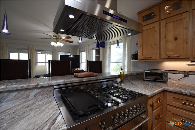 kitchen with a wealth of natural light, ceiling fan, stainless steel stove, and island range hood