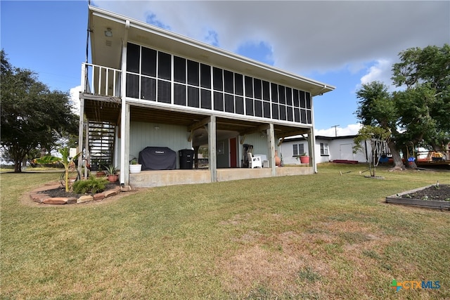 rear view of house with a sunroom and a lawn