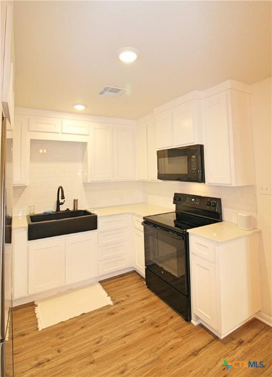 921 N 10th St, Temple, TX 76501 - kitchen featuring black appliances, white cabinetry, light countertops, and recessed lighting