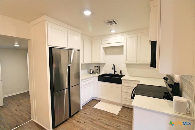 921 N 10th St, Temple, TX 76501 - kitchen featuring stainless steel fridge, black electric range, backsplash, light countertops, and recessed lighting
