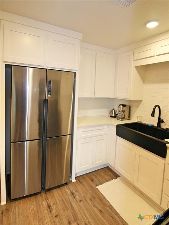 921 N 10th St, Temple, TX 76501 - kitchen featuring high end fridge, white cabinets, light wood-style flooring, light countertops, and backsplash